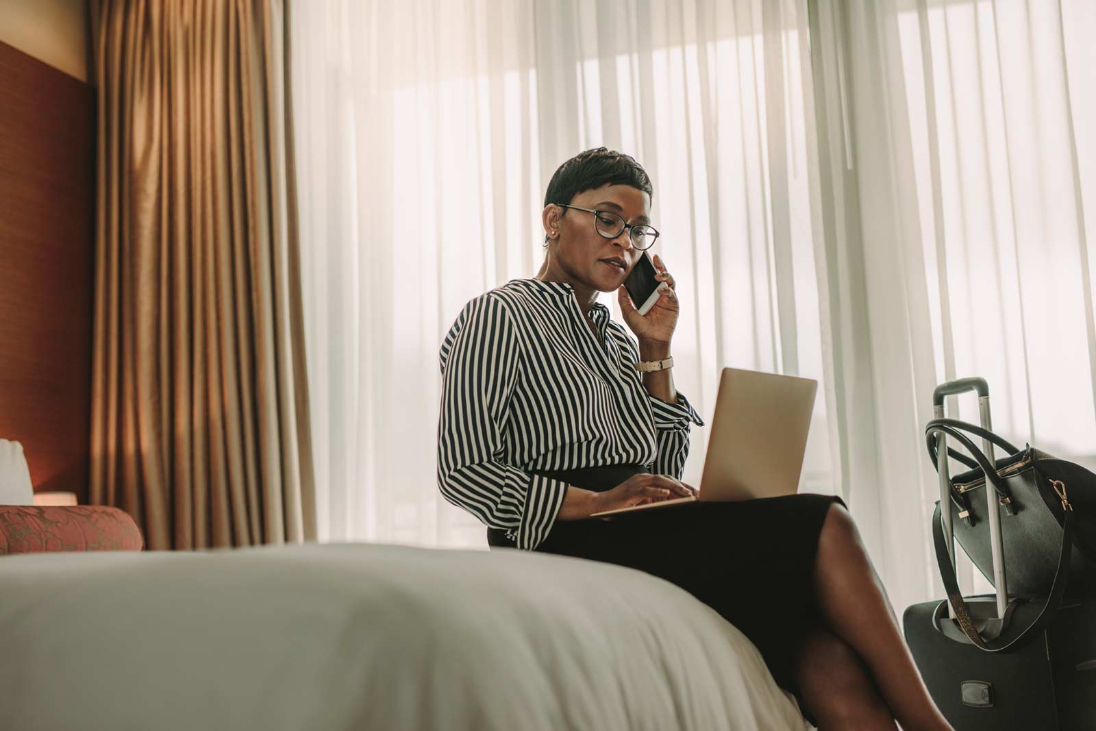 Mulher de negócios feliz e confortável numa cama de hotel