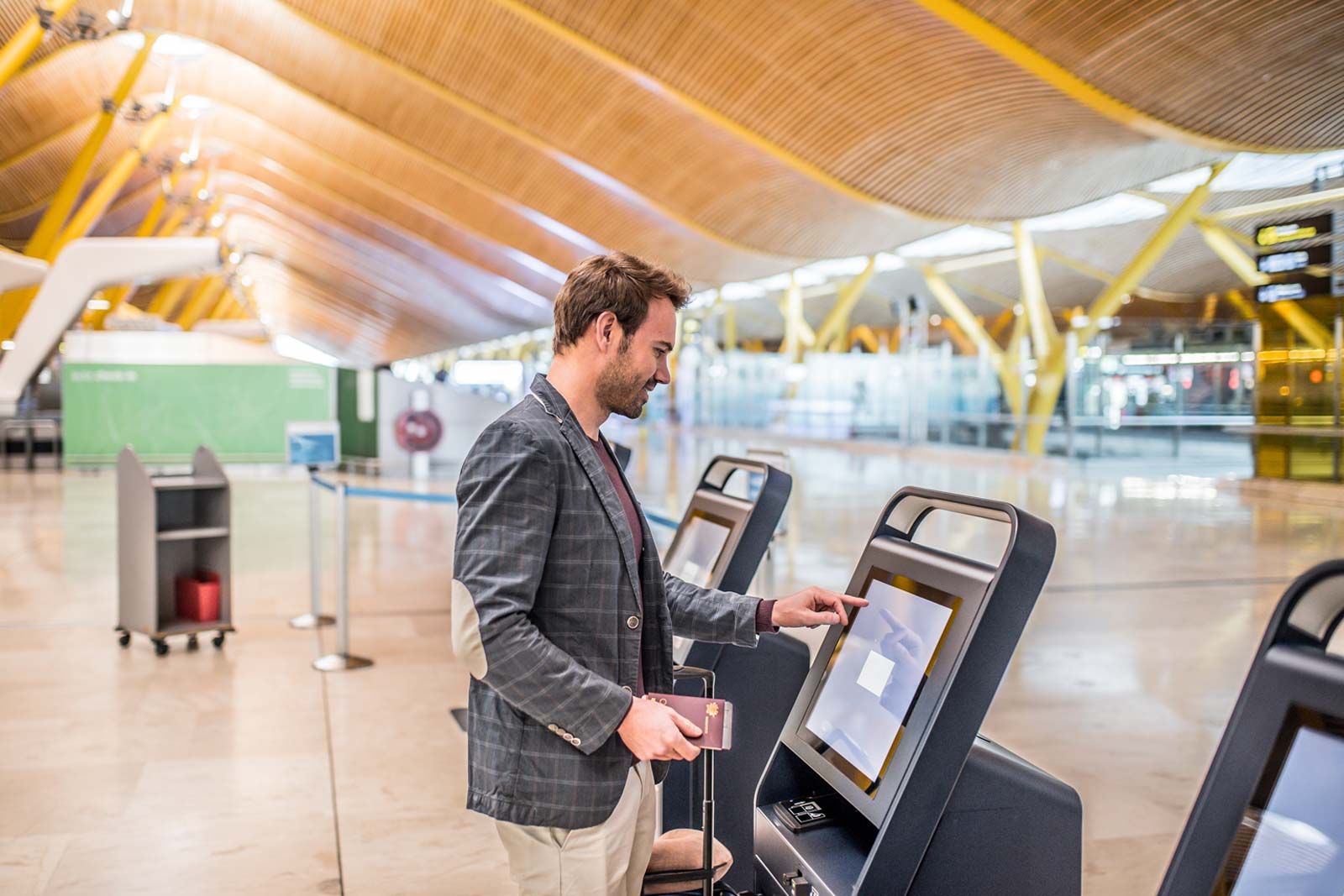 Happy man using the check-in machine at the airport getting the boarding pass