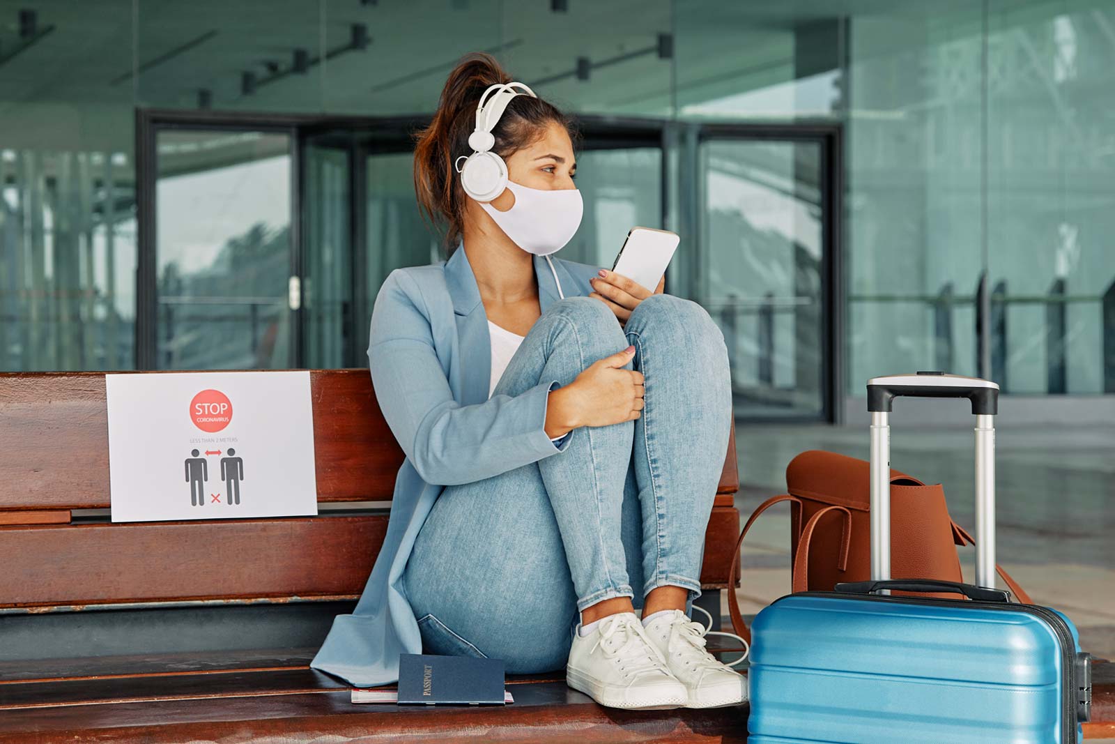 Woman with COVID-19 mask and headphones in the airport during pandemic