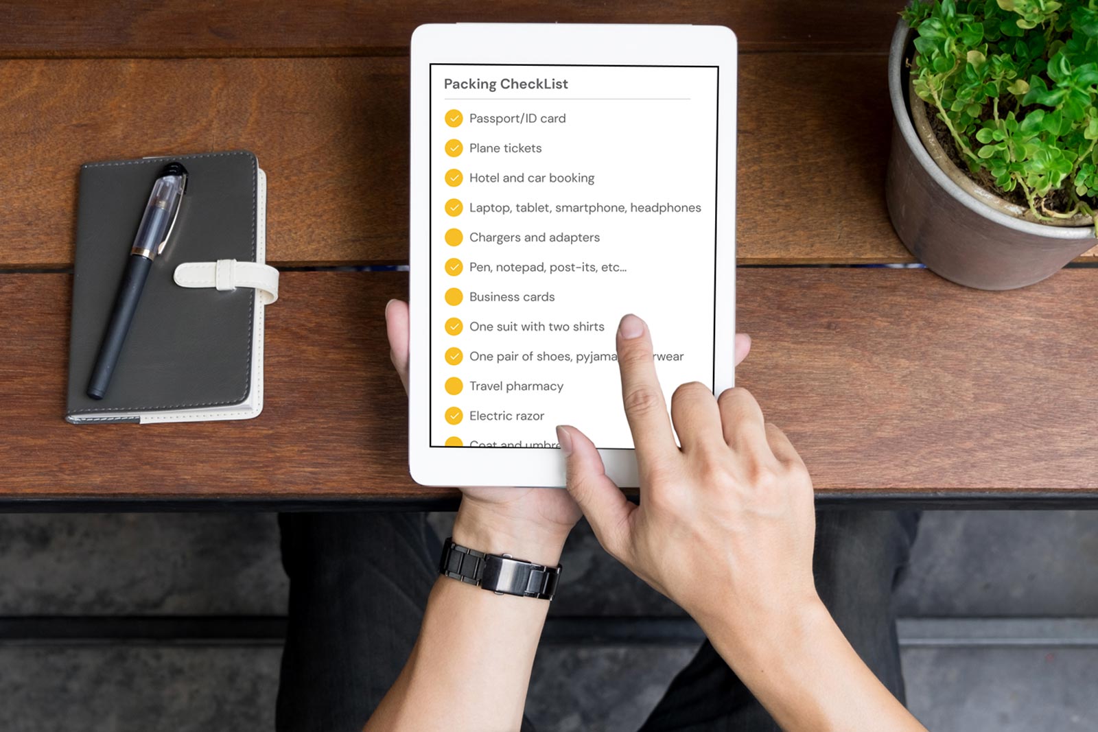 Man using a tablet to organize the things he needs to take on his business trip
