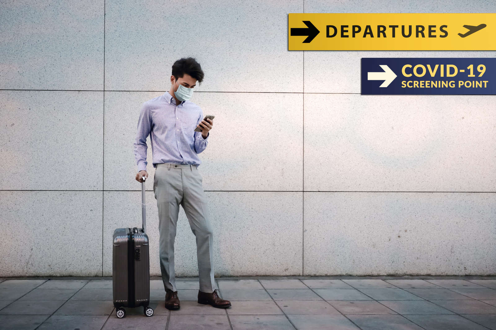 Young Businessman wearing a surgical mask and a smartphone standing with his luggage at the airport