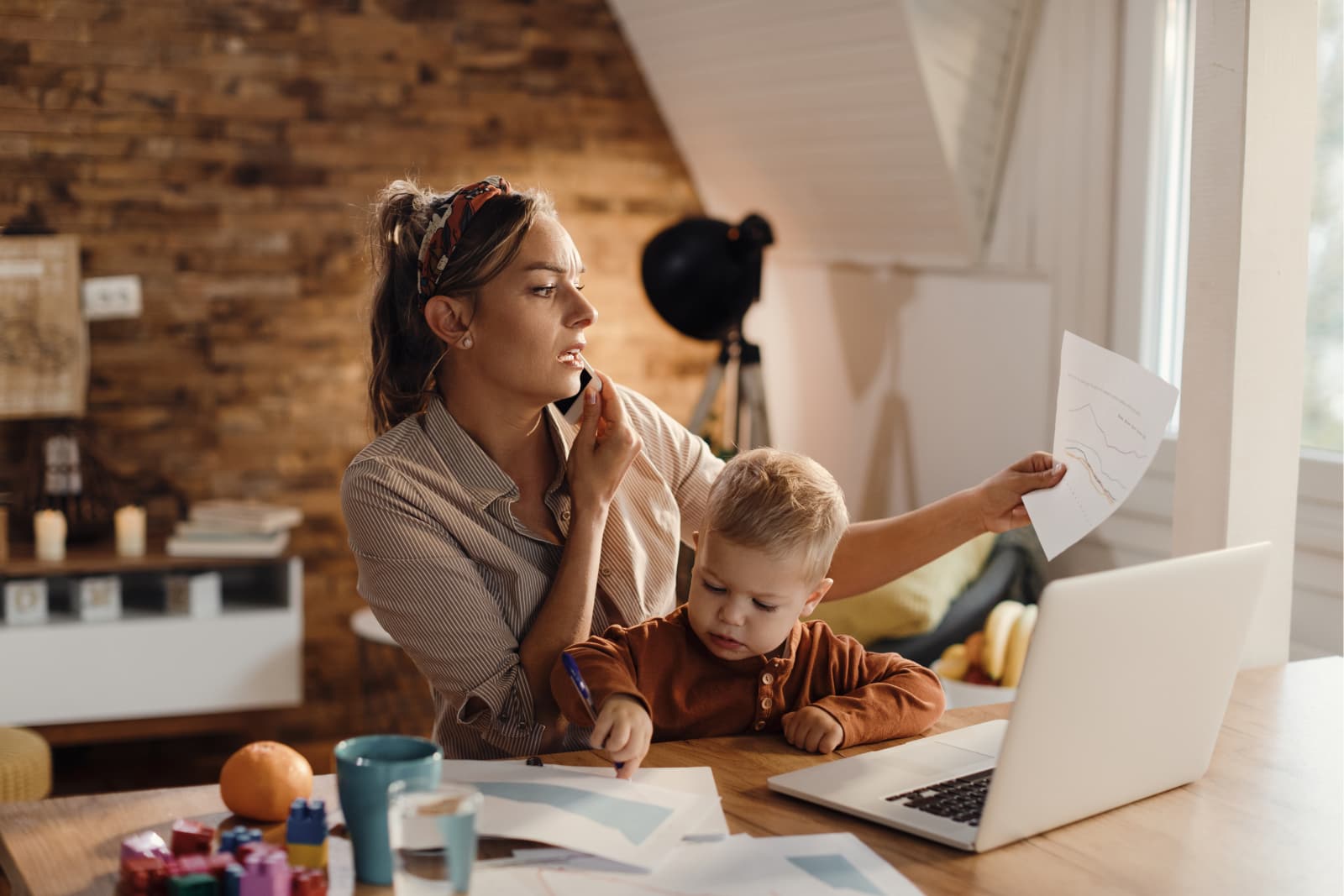 Mãe analisando relatórios de negócios enquanto fala no telefone